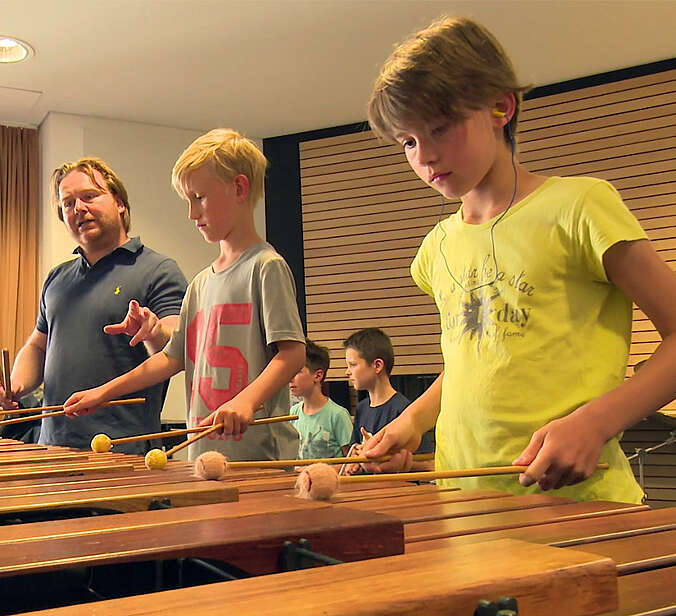 Zwei Kinder spielen Perkussin vor Lehrer