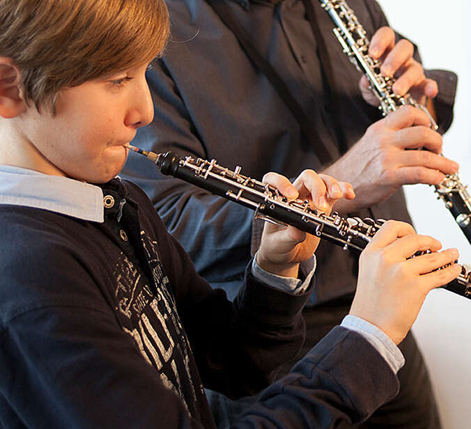 Junge und Lehrer spielen gemeinsam Oboe
