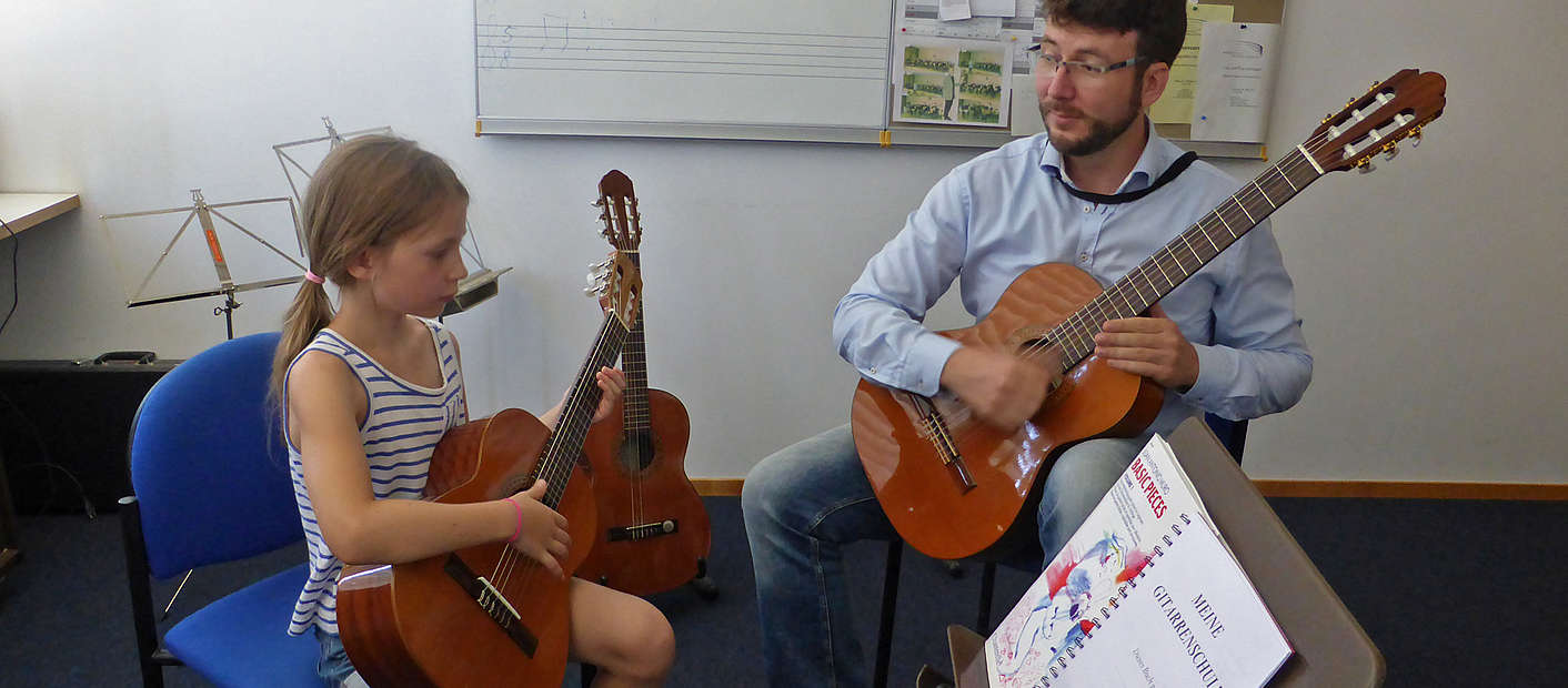 Lehrer und Schülerin während Gitarrenunterricht
